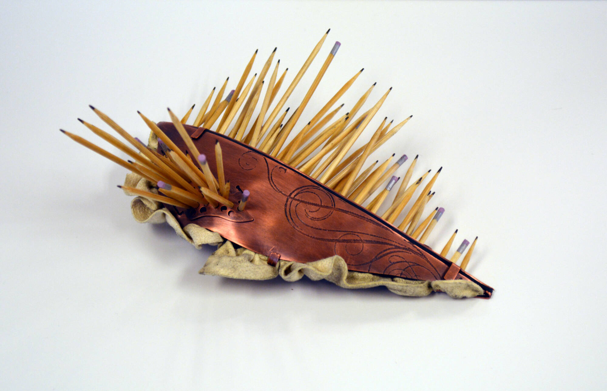 Small brooch made of different materials that looks like a slug with spikes.